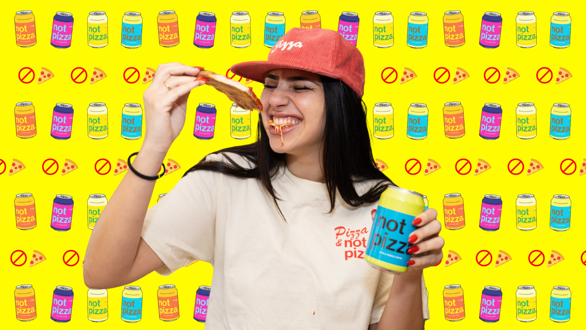 A woman in a red cap biting a slice of pizza while holding a not pizza vodka lemonade can in a sunlit kitchen